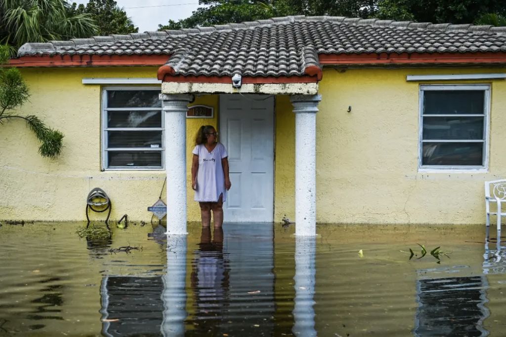 Woman standing in front of her flooded home after a hurricane